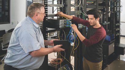 Image of a student and teacher working on IT servers