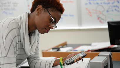 A woman working on an assignment holding a calculator