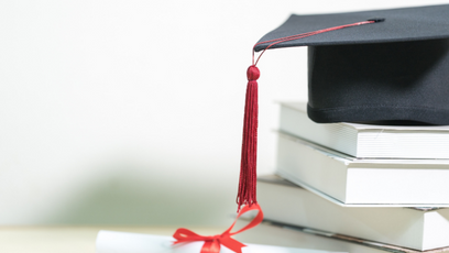 A stack of books with a graduation cap on top
