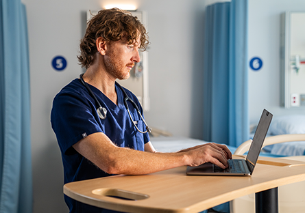 Casey Anderson working at a laptop in a healthcare setting.