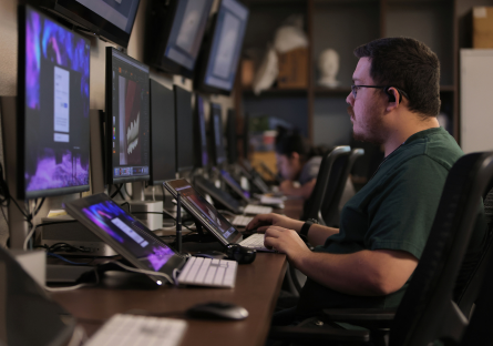 A Maricopa Community Colleges information technology student using multiple computer screens.