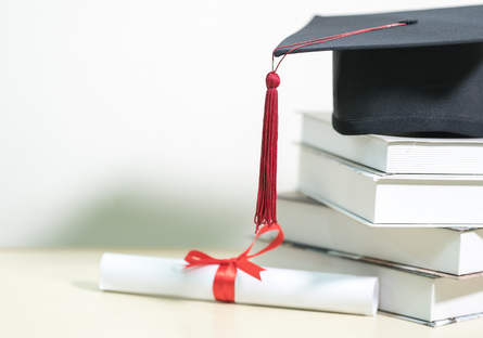 Image of a graduation cap on top of a stack of books