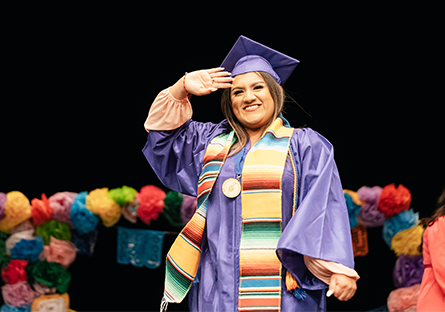 An image of a female student wearing a graduation cap, gown, and colorful stole attending a Hispanic Convocation Ceremony