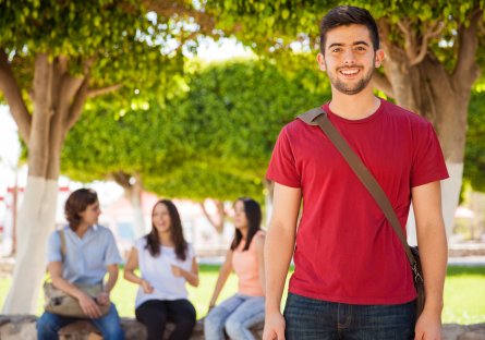 An image of a male college student wearing a red T-shirt with three women sitting on a bench in the background