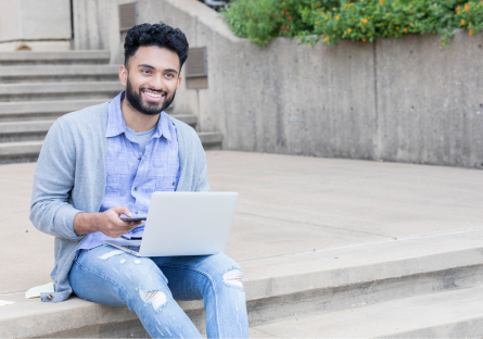 An image of a man sitting on steps using a laptop