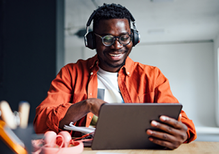 Male student wearing headphones working an a tablet 