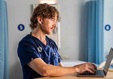 Casey Anderson working at a laptop in a healthcare setting.