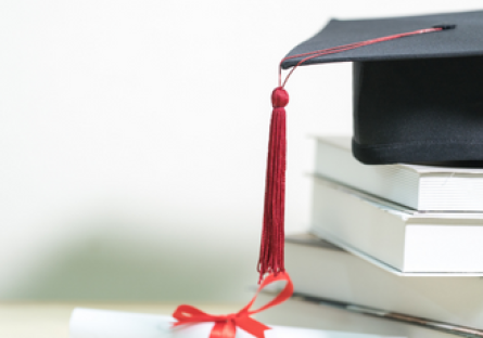 Image of a graduation cap on top of a stack of books