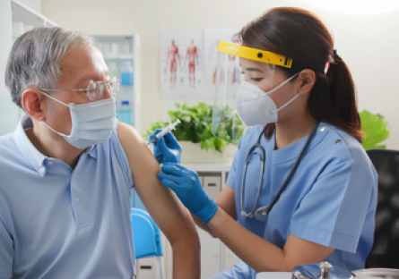 Image of a woman doctor wearing a face mask giving a male patient wearing a face mask a shot