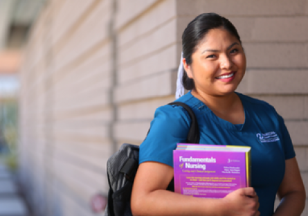 Smiling nursing student wearing scrubs and holding books